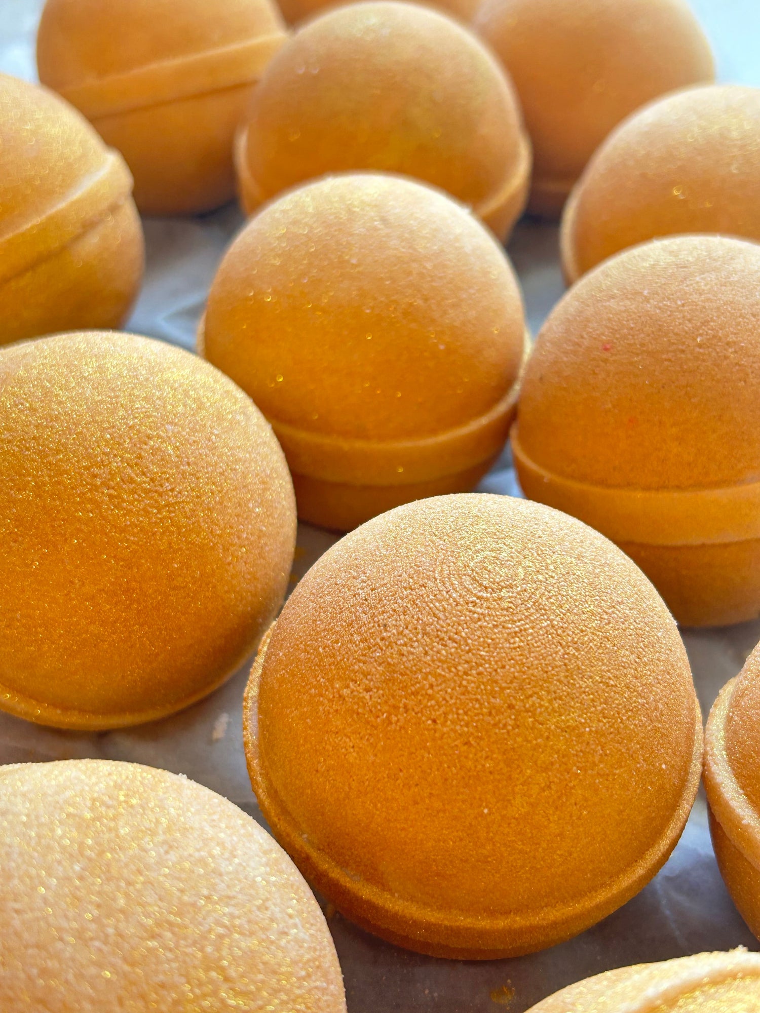 Round golden-orange bath bomb domes with textured surface