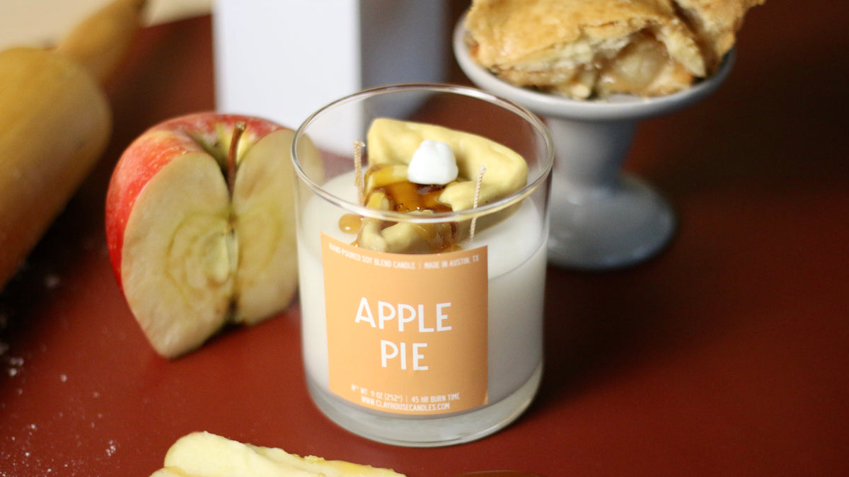 Apple pie container candle in clear glass jar with orange label and wax topping