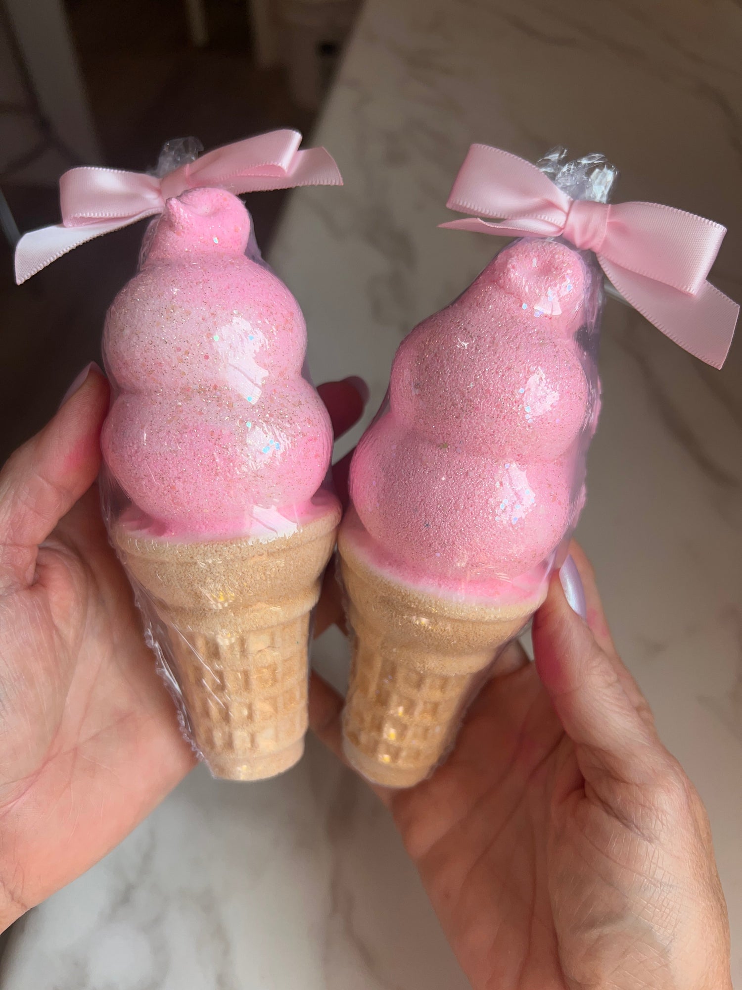 Pair of pink ice cream cone bath bombs with glittery scoops and pink bows