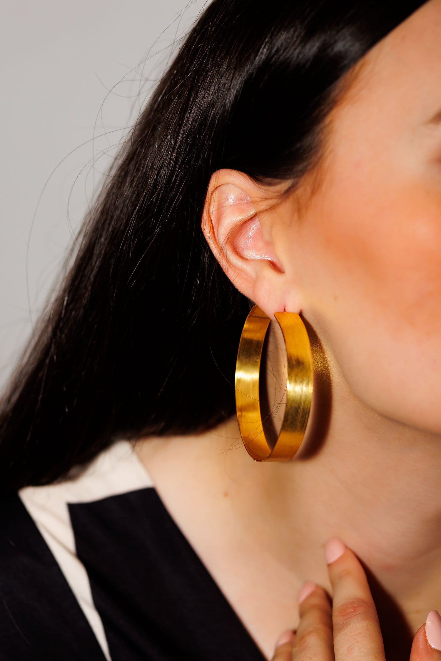 Gold hoop earrings on model, large oval hoops with polished shine