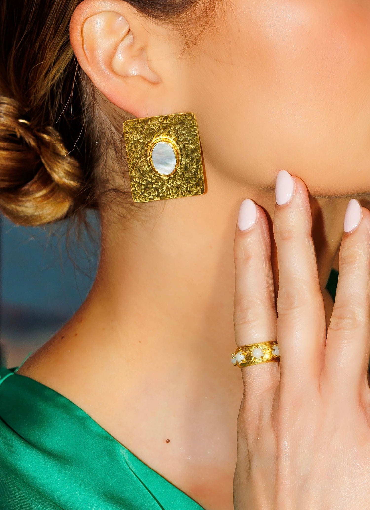 Gold square stud earrings with hammered texture and oval center cutout.