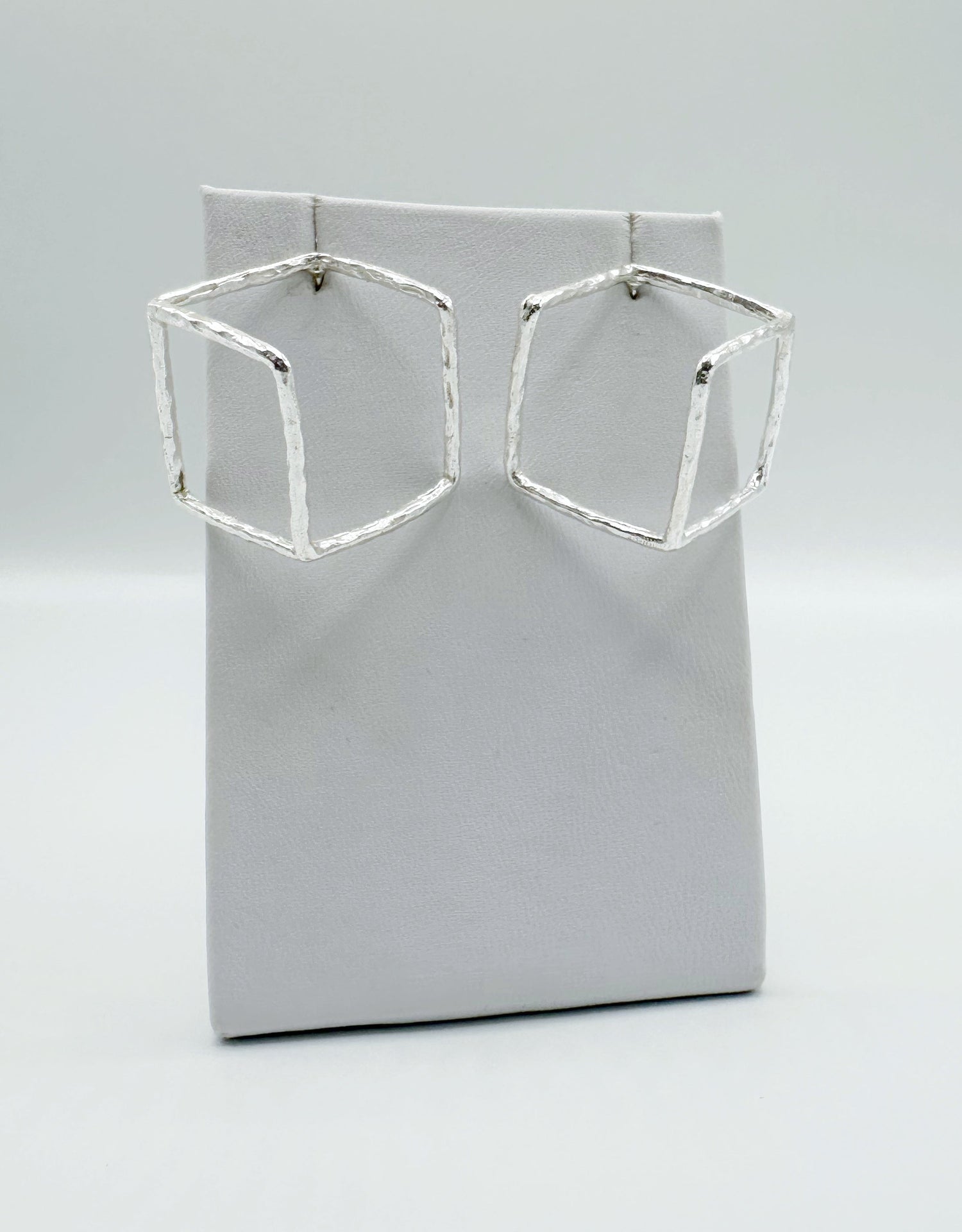 Silver geometric open-square wire earrings shown on a white display card