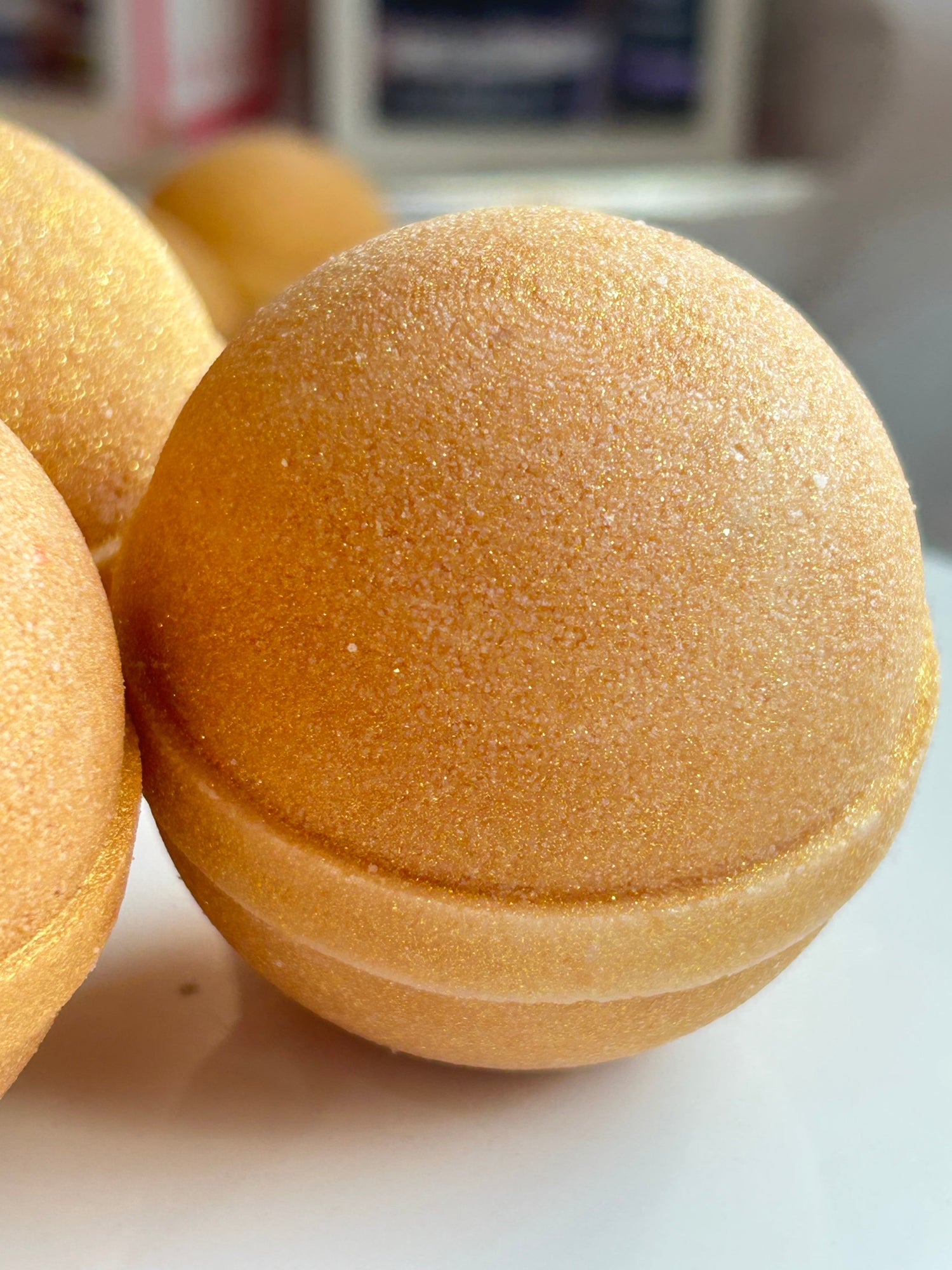 Single golden bath bomb dome with glittery textured top and ridged base