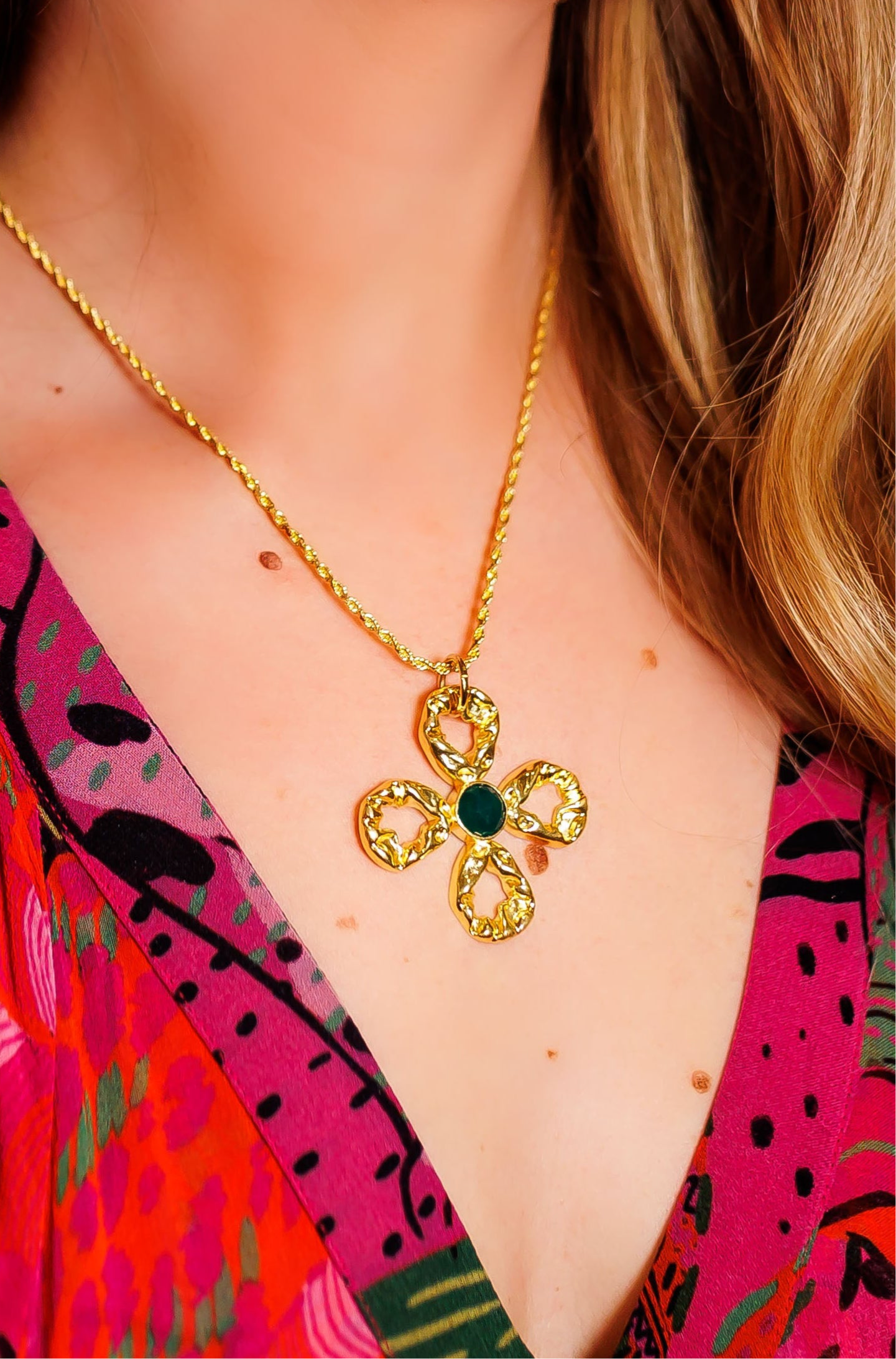 Gold-tone chain necklace with quatrefoil flower pendant and dark green center bead.