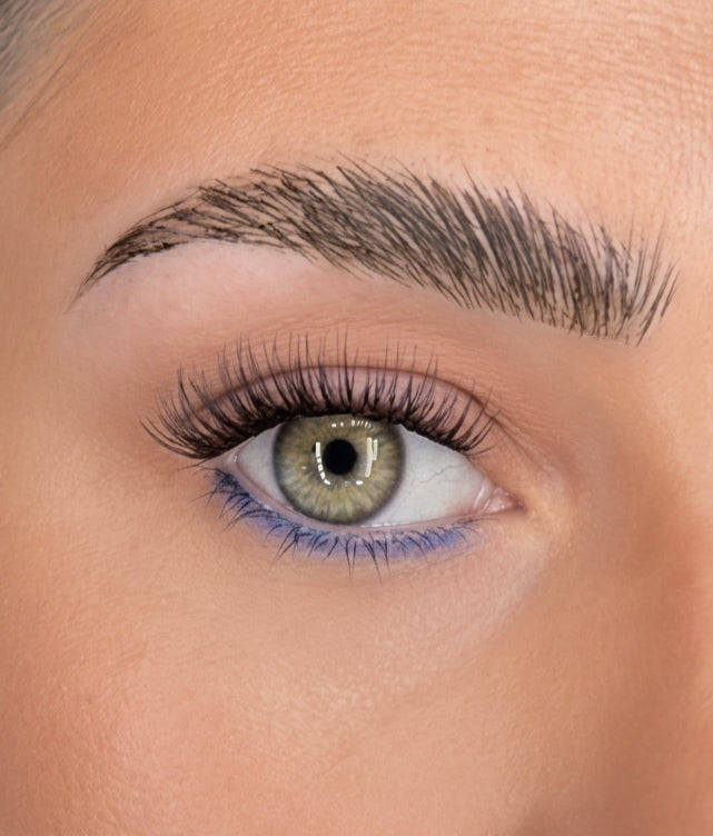 Curled eyelash extensions on green eye, long wispy lashes and defined brow