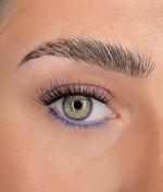 Curled eyelash extensions on green eye, long wispy lashes and defined brow