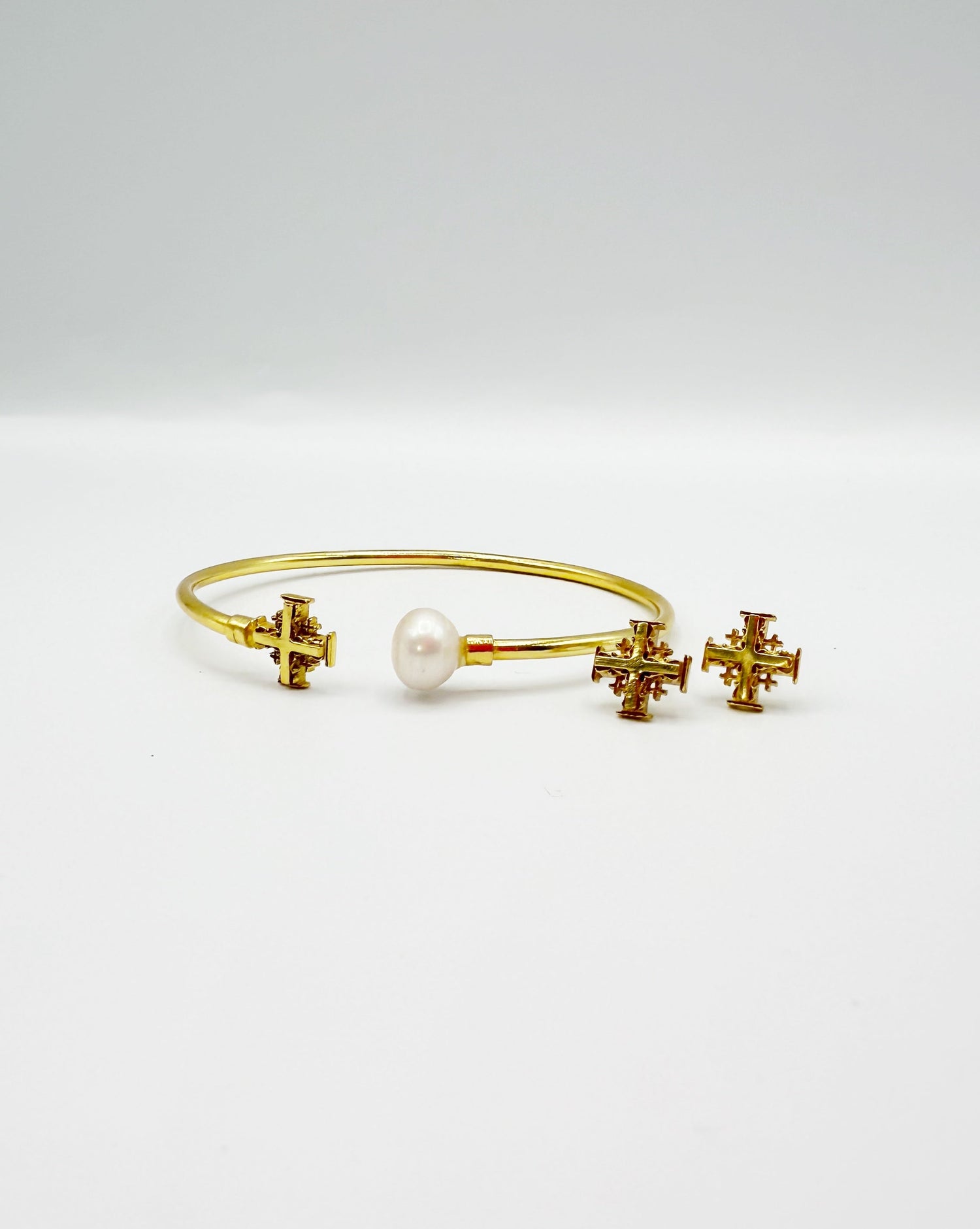 Gold cuff bracelet with pearl and cross charms