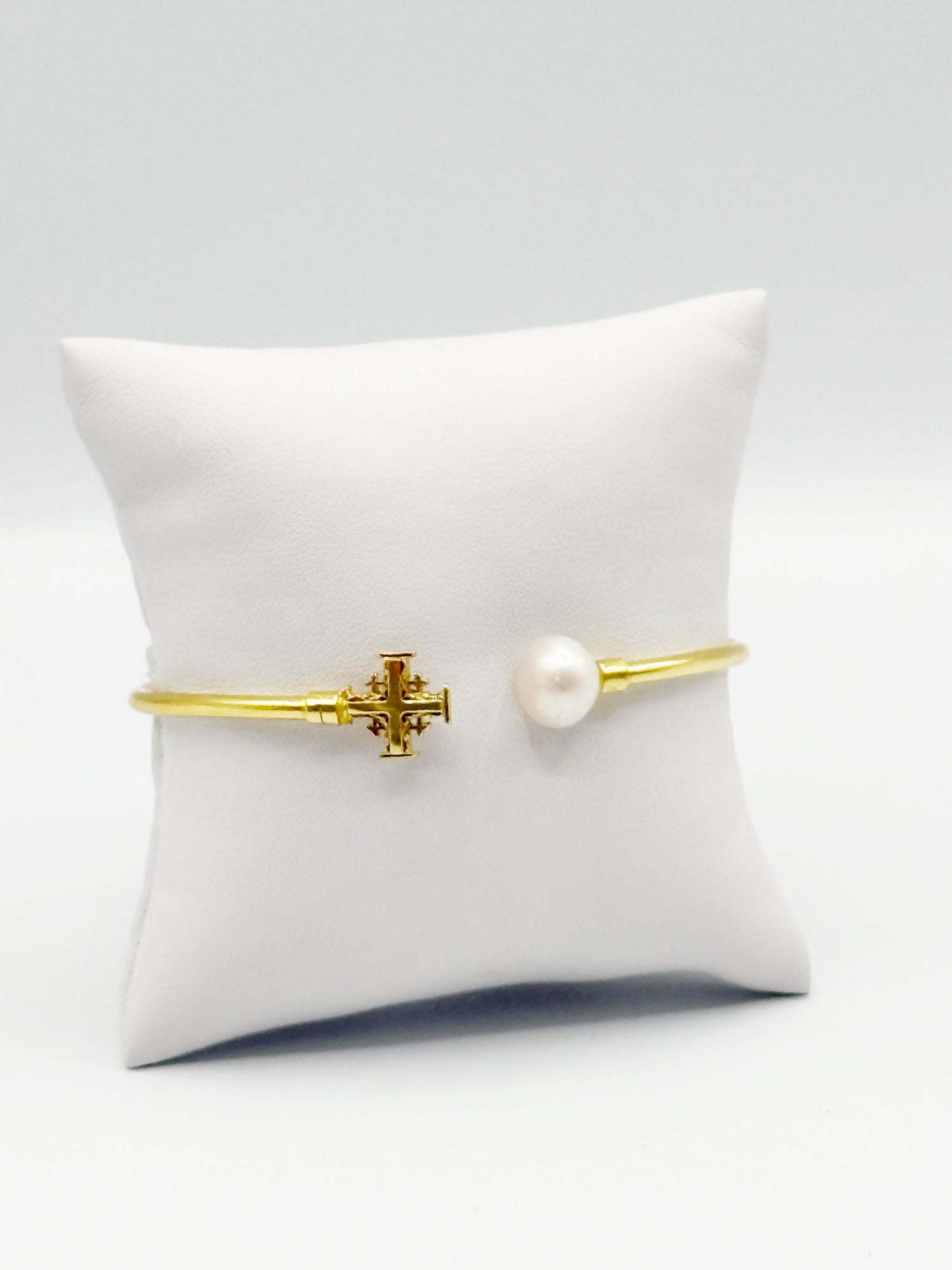 Gold bracelet with central cross charm and white pearl bead on slim band