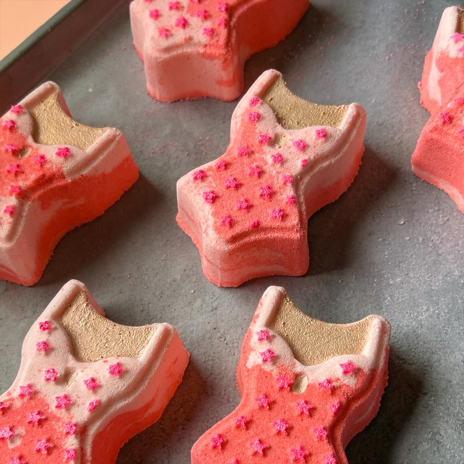 Swimsuit-shaped bath bomb pieces, red and beige with pink flower sprinkles