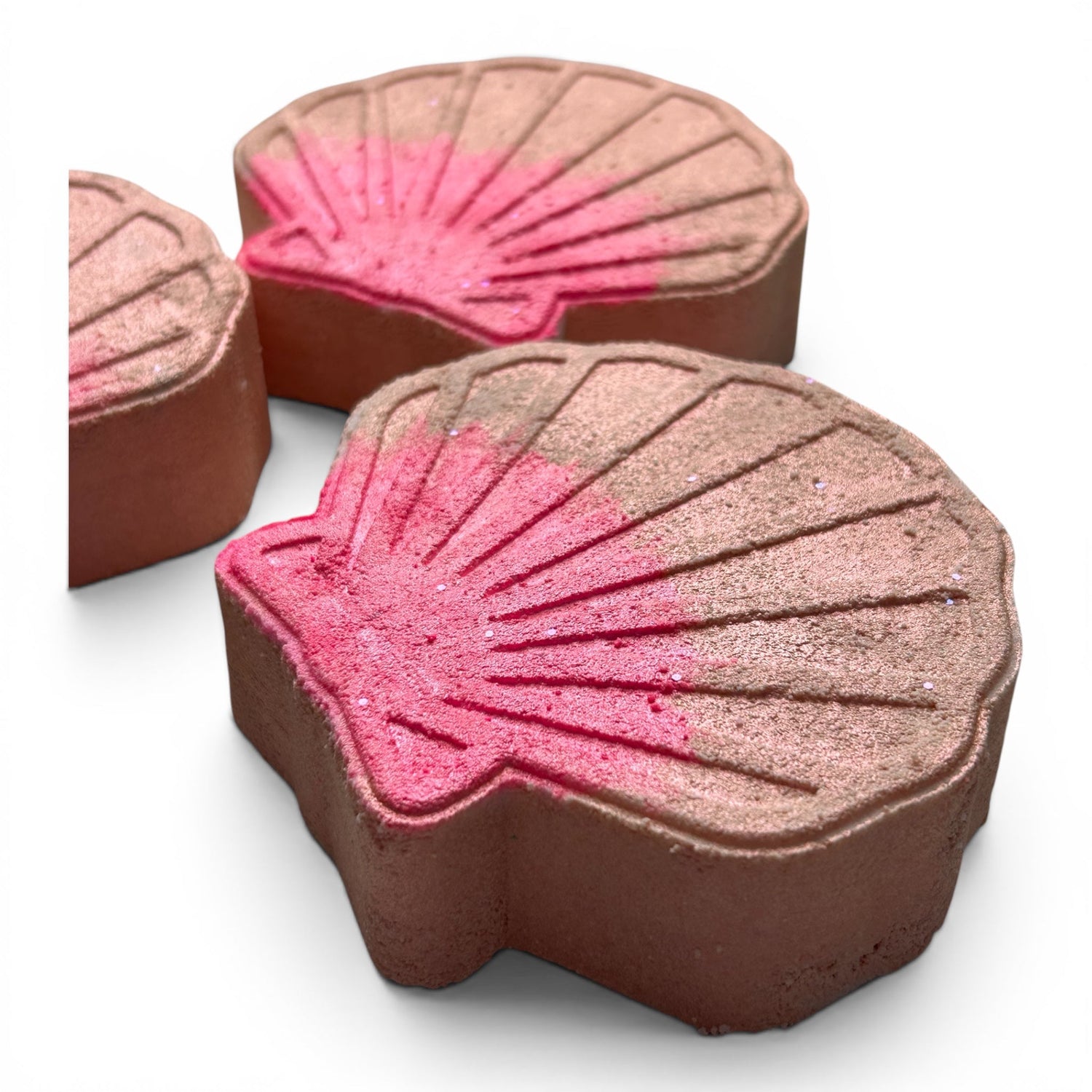 Shell-shaped bath bomb with bright pink ridged top and dark brown base, stacked set