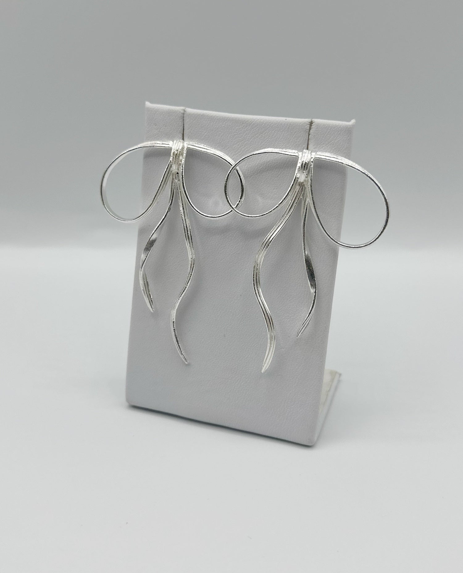 Silver-tone hoop earrings on display card with dangling fringe