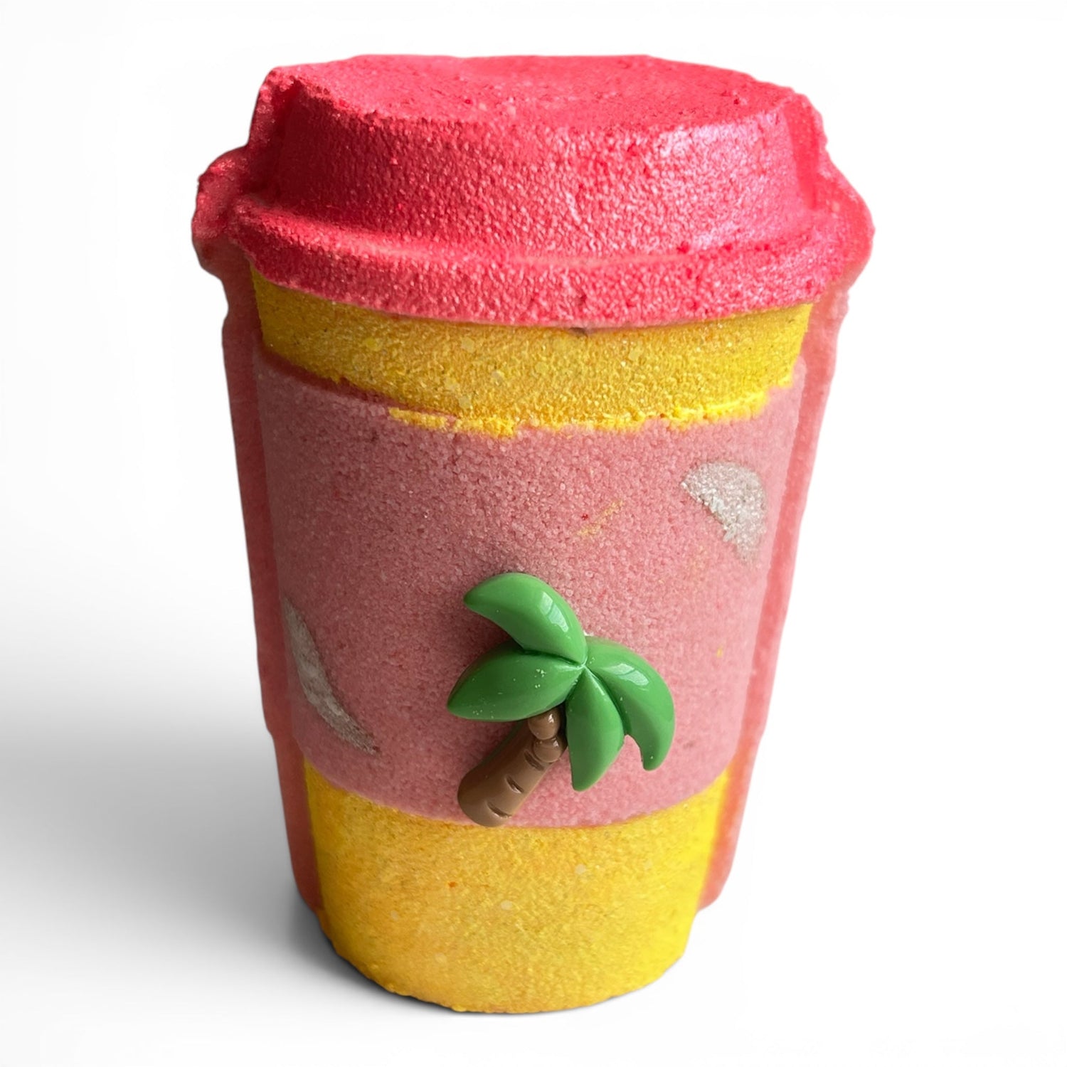 Cup-shaped bath bomb with red top, yellow base, and green leaf decoration