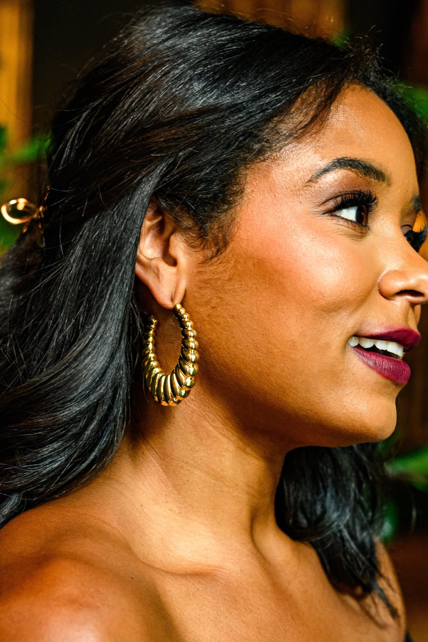 Gold hoop earrings with ridged spiral design, close-up on ear
