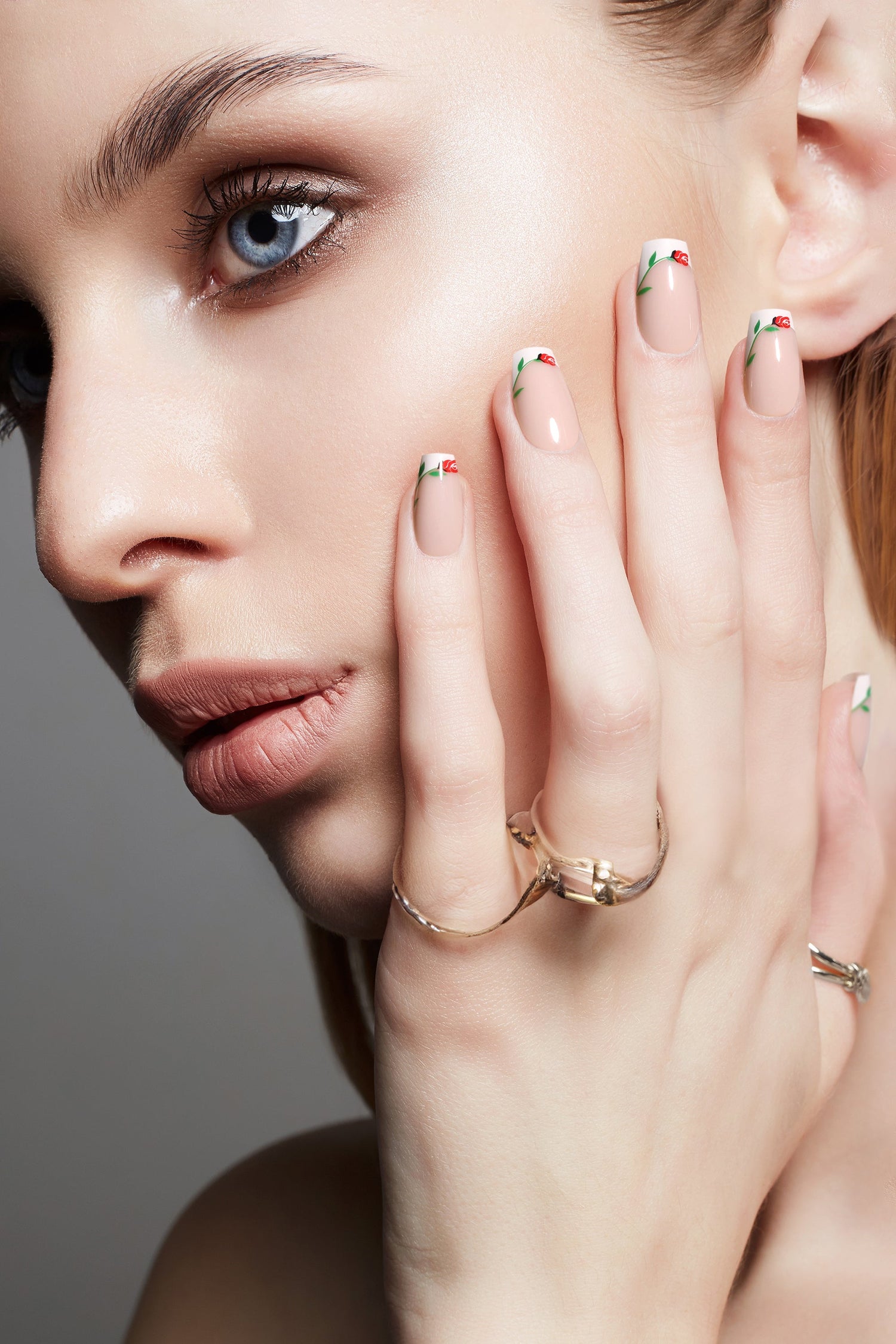 Short press-on nails on hands with pale pink base and red rose floral tips