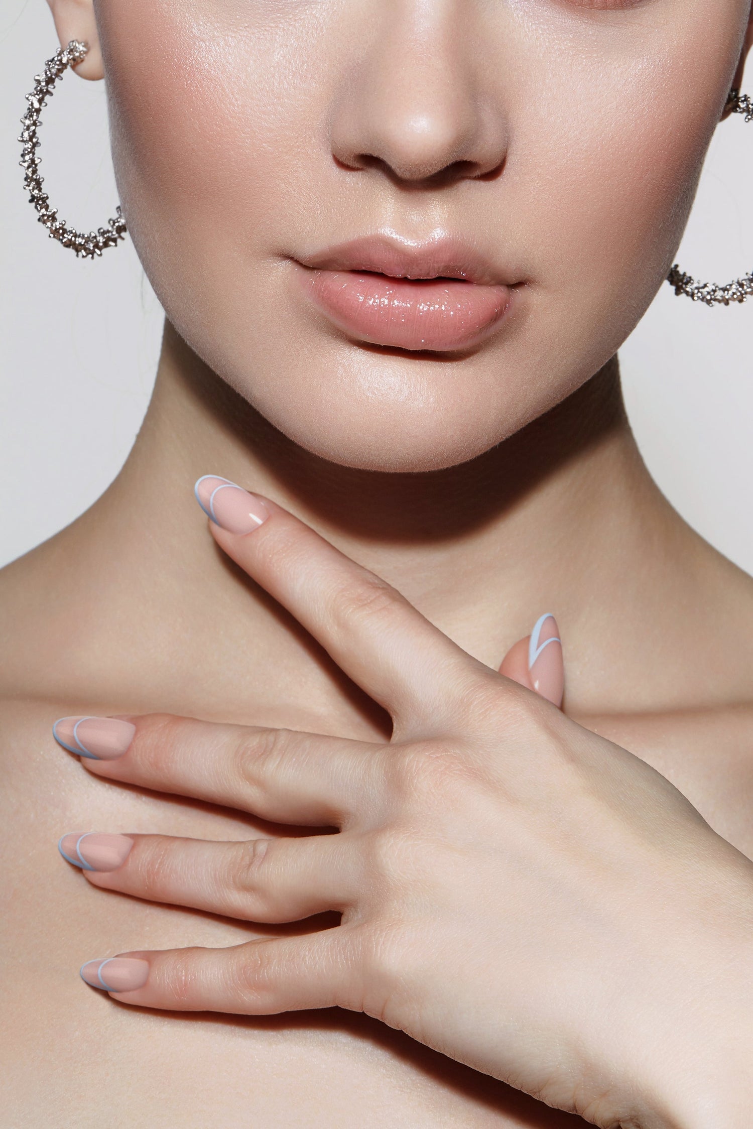 Pastel pink press-on nails with blue crescent tips on hands and wrist