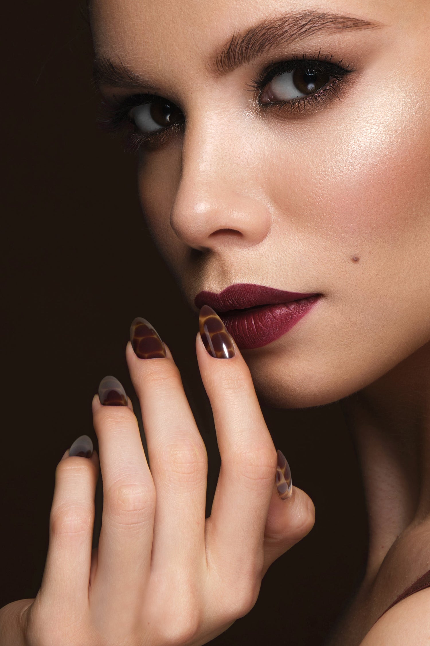 Set of press-on nails on a hand with glossy brown giraffe-pattern tips