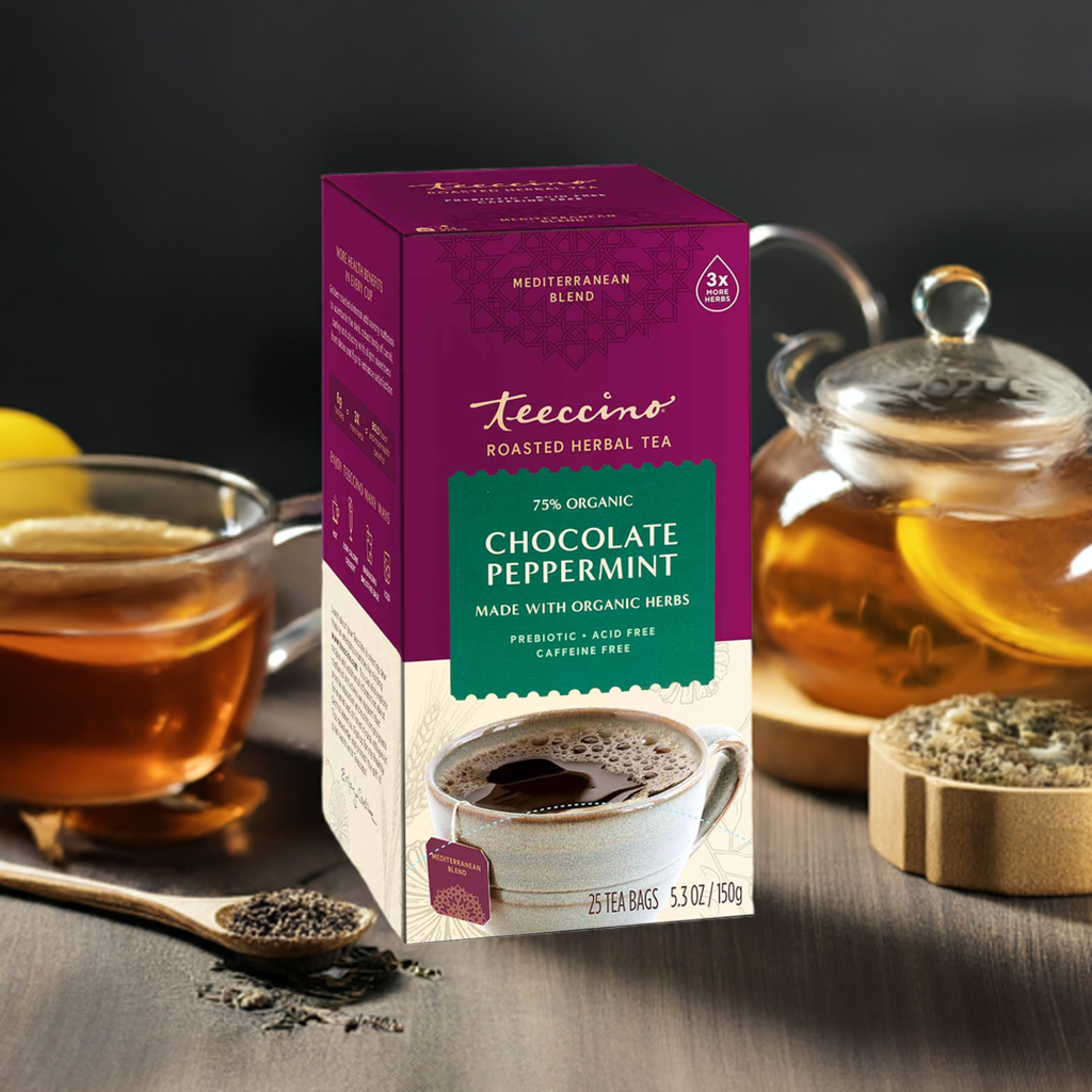 Roasted herbal tea box beside cups of tea and scattered tea leaves on a table.