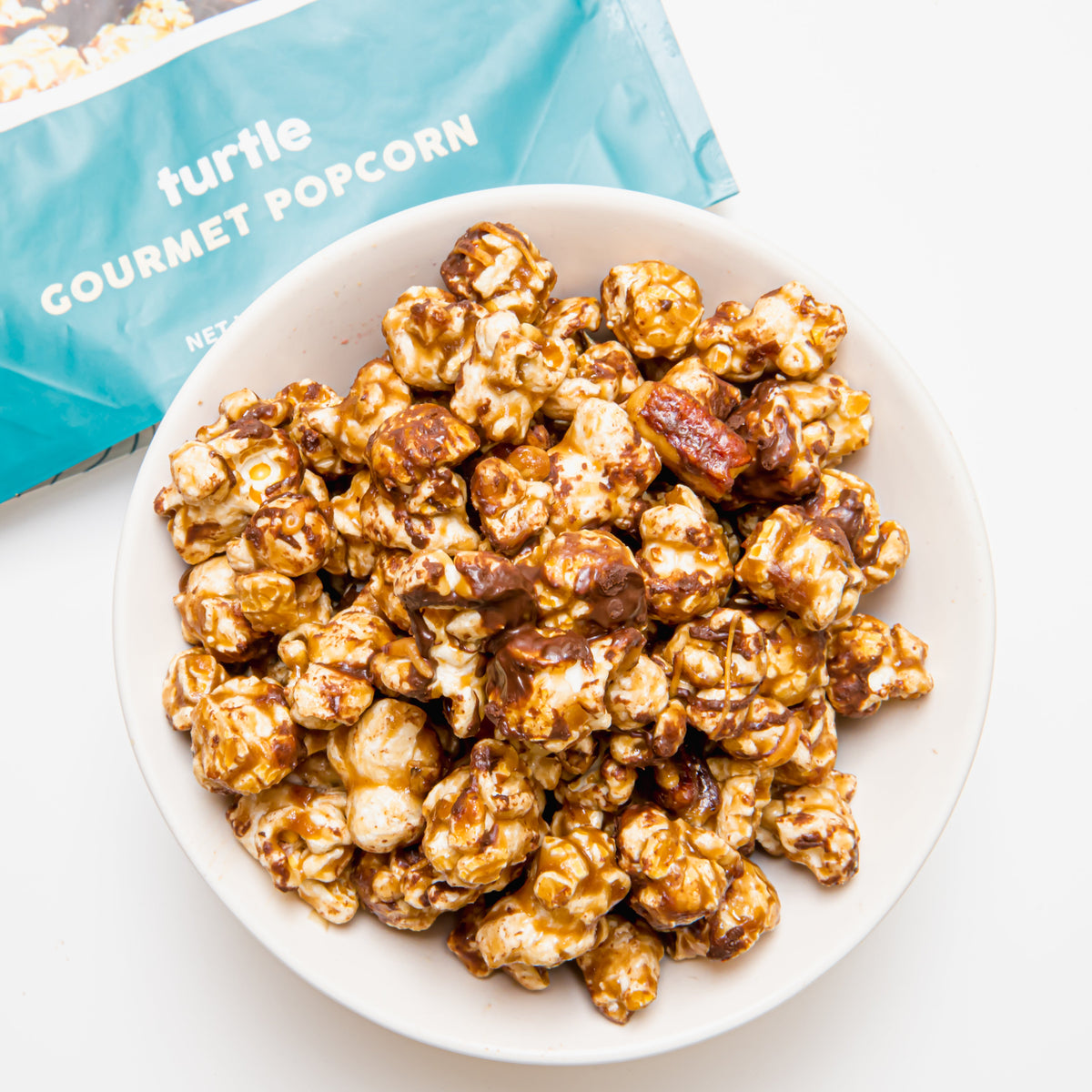 Bowl of turtle gourmet popcorn with caramel and chocolate, golden-brown mix