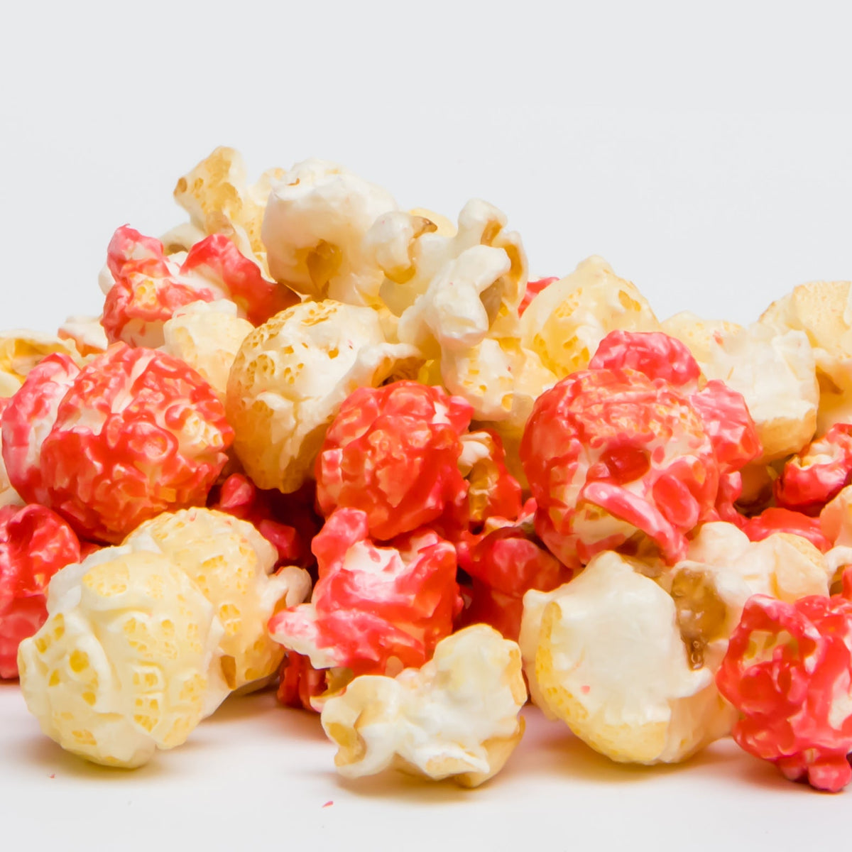 Strawberry cheesecake flavored popcorn, red and white craggy clusters