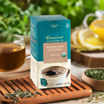 Roasted dandelion coconut herbal tea box on tray with cup of dark tea