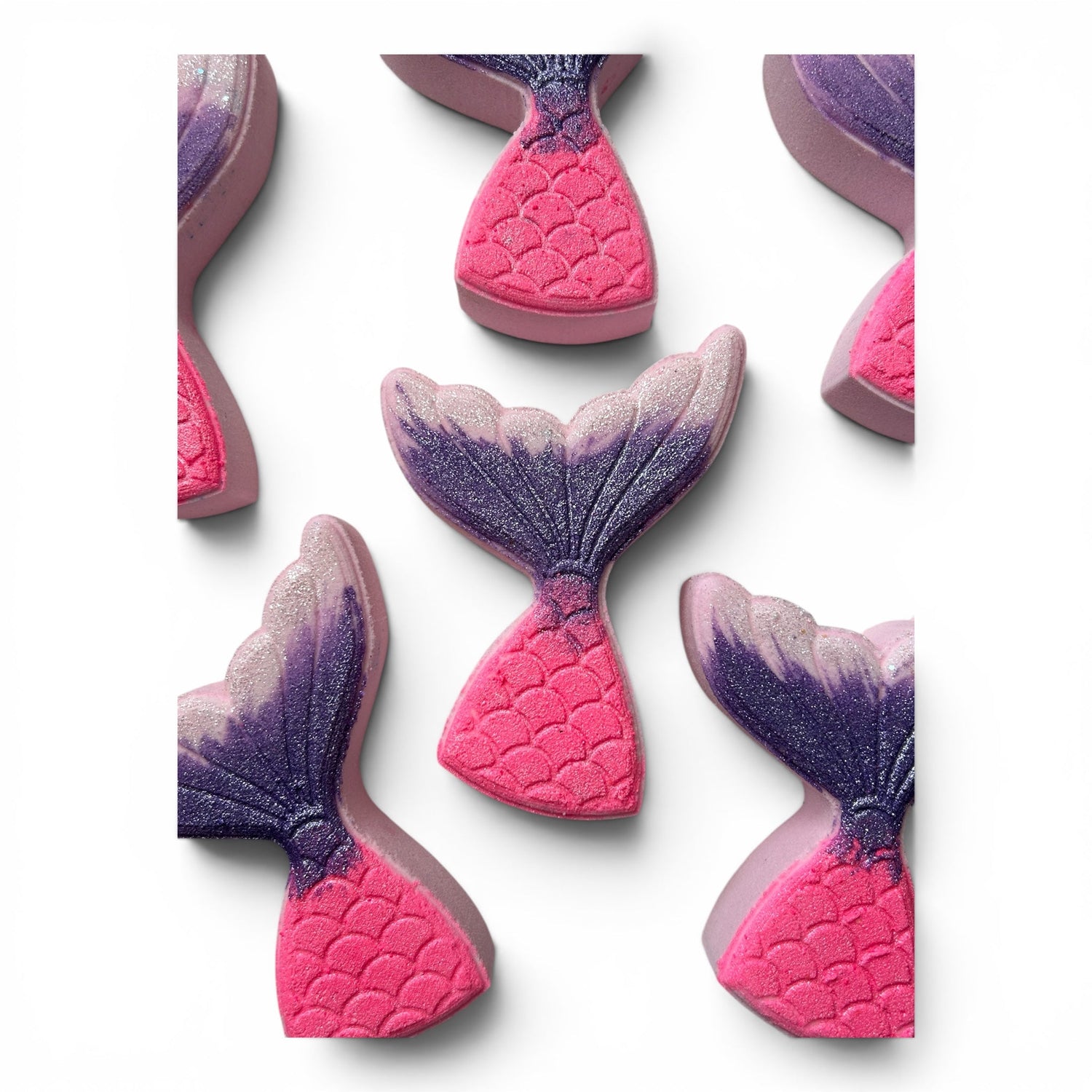 Set of mermaid tail bath bombs in pink with purple glitter tops, angled views
