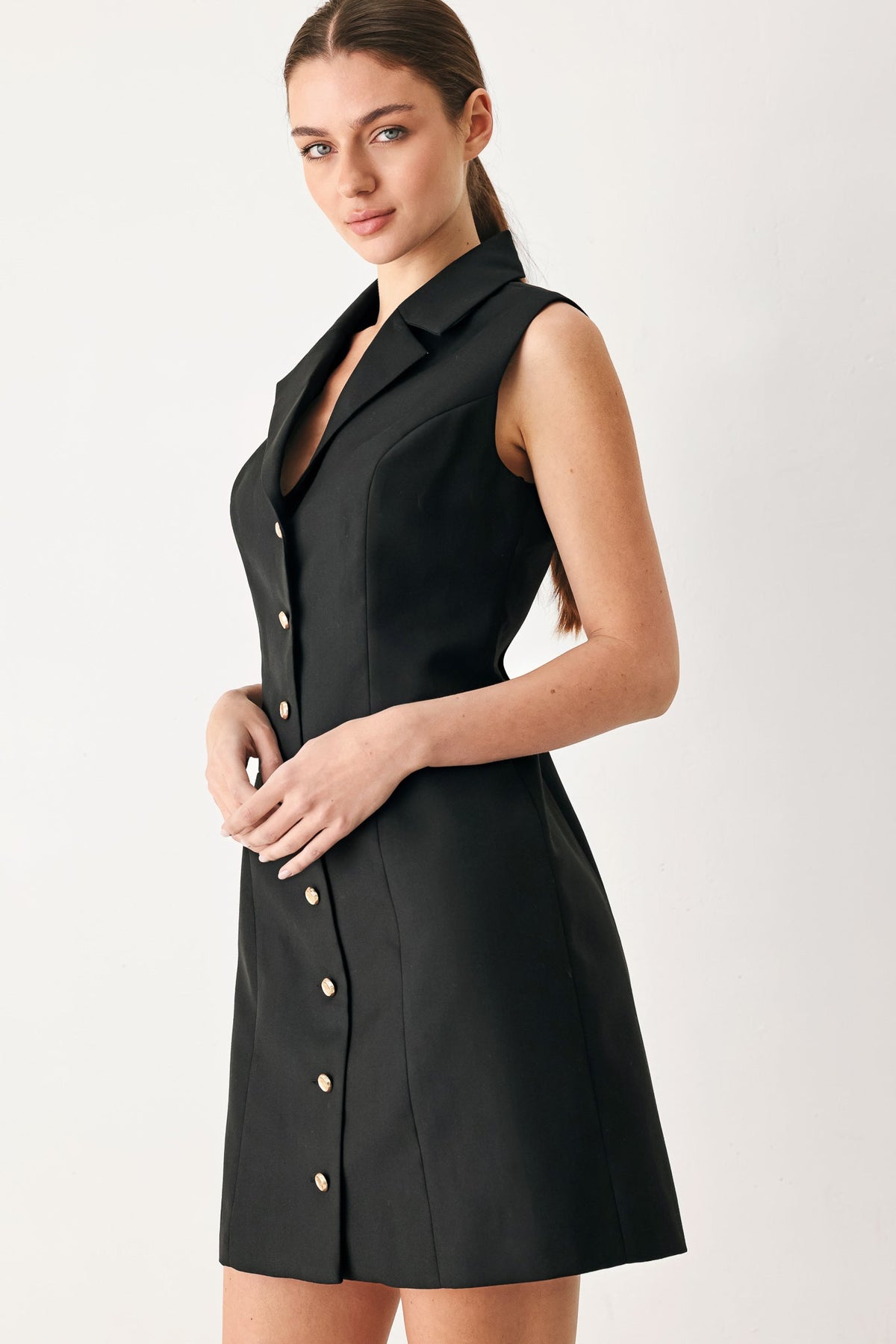 Black sleeveless woven mini dress with deep V neckline, point collar, gold buttons