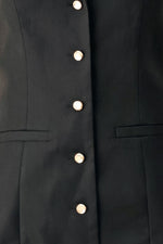 Black woven mini dress detail: gold buttons and patch pockets