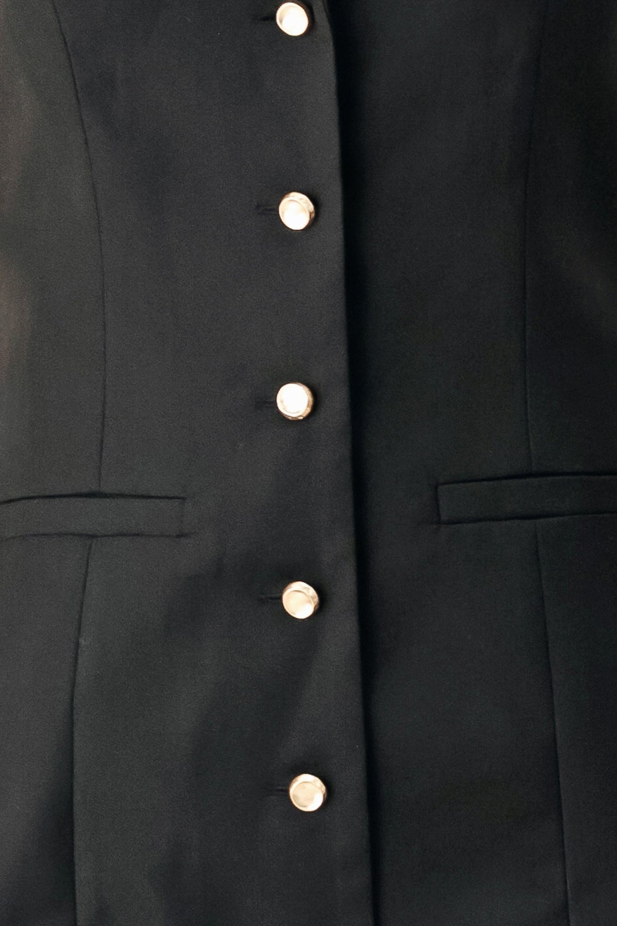 Black woven mini dress detail: gold buttons and patch pockets