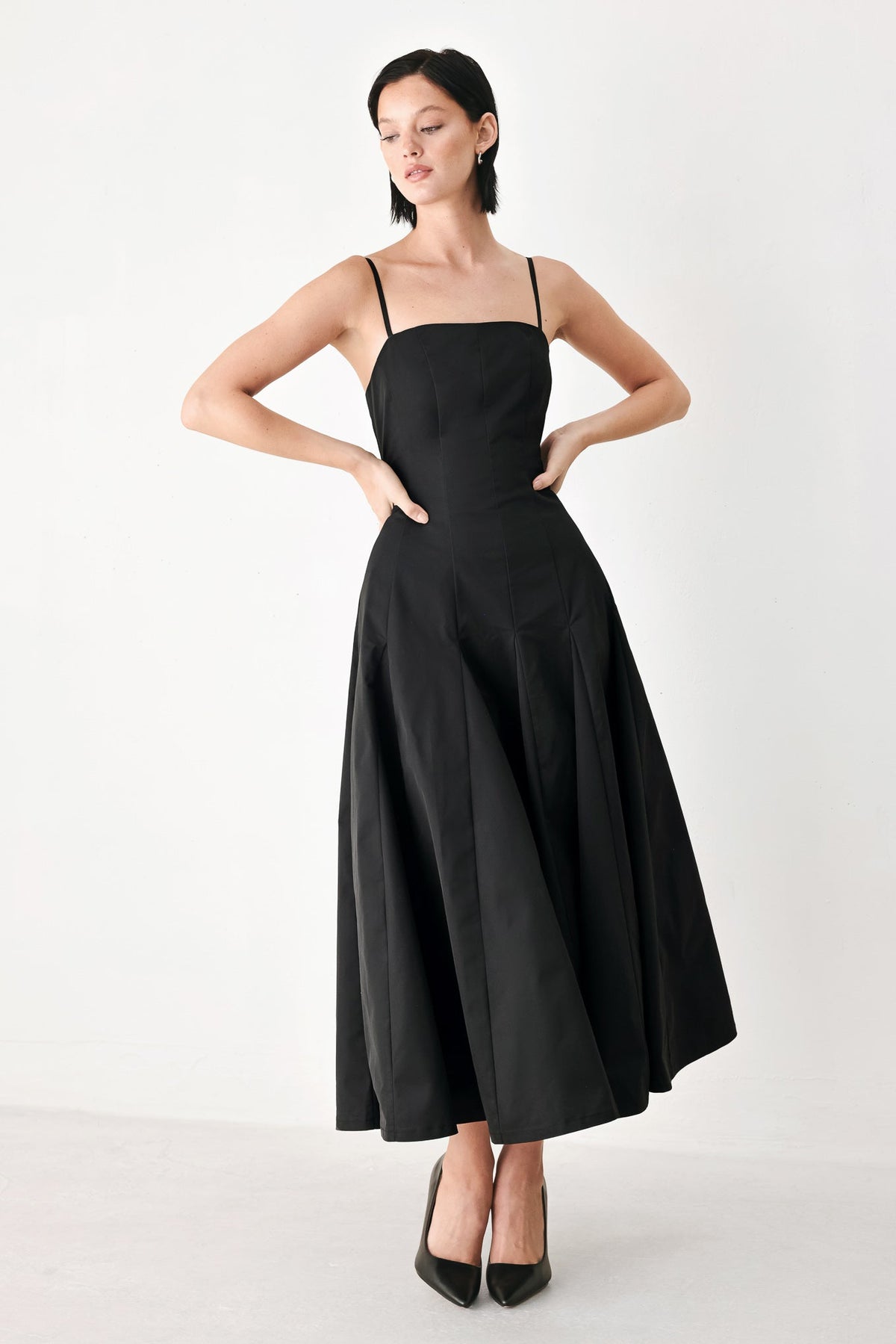 Black midi dress with thin shoulder straps and gathered waist, full midi skirt