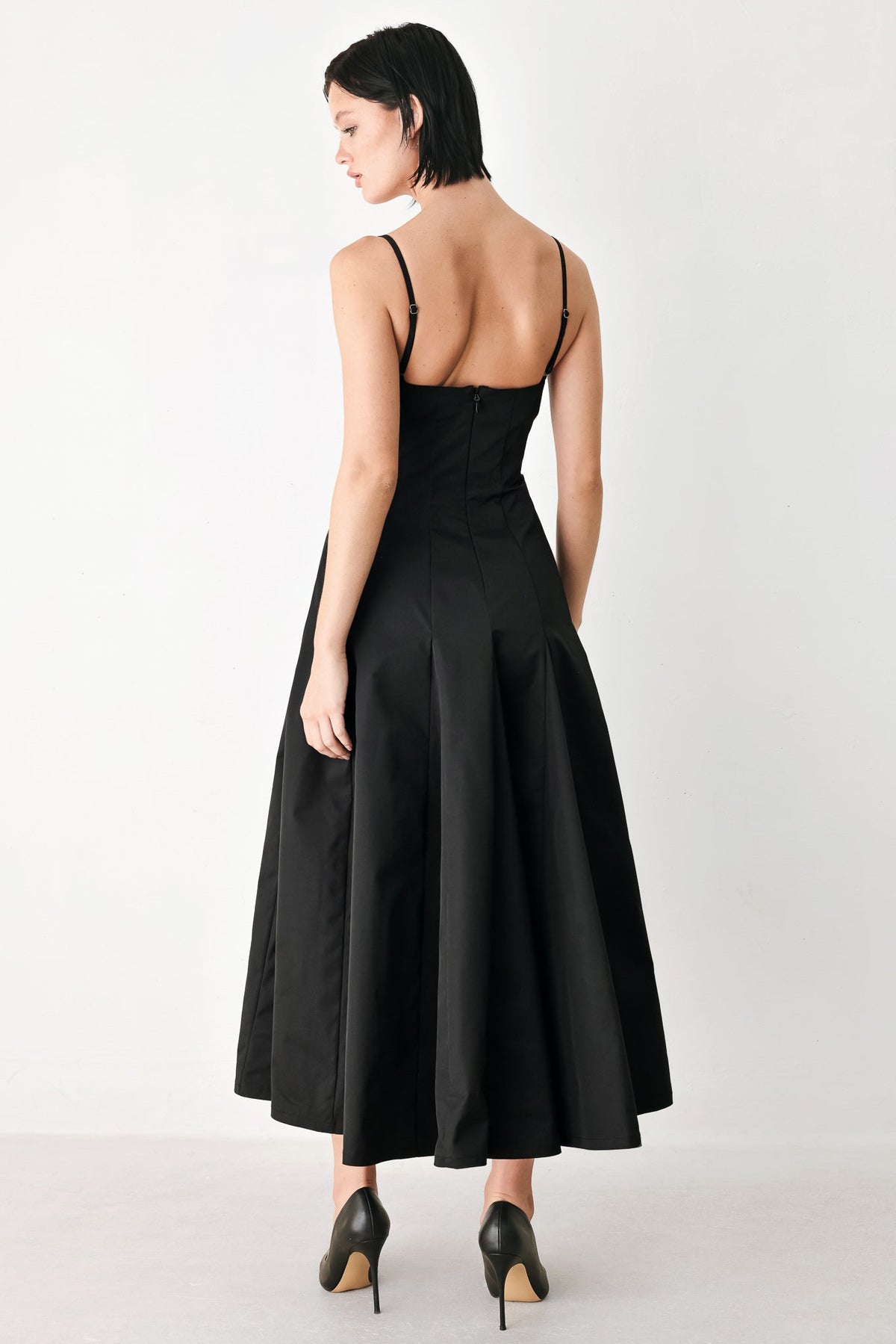 Back view of black midi dress with thin straps and flared pleated skirt