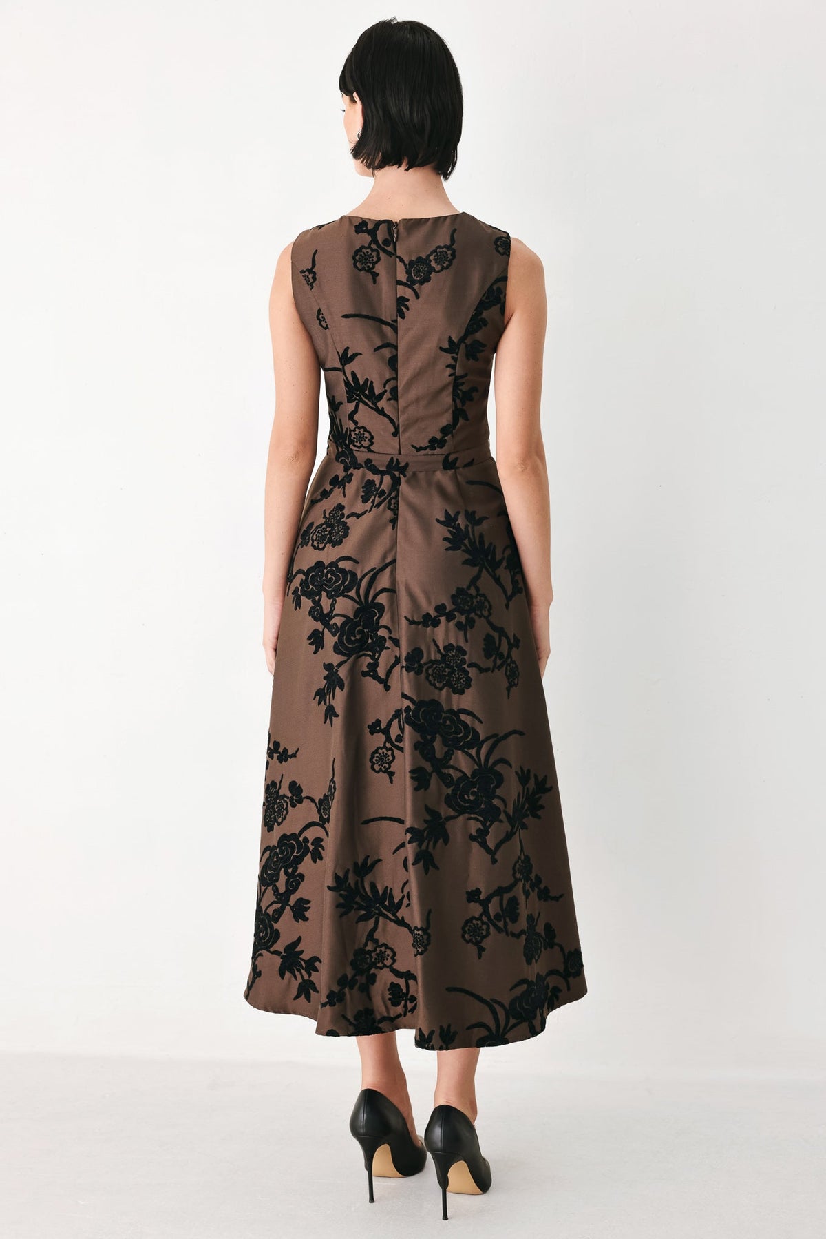 Brown woven midi dress with black floral pattern, sleeveless back view and waist belt