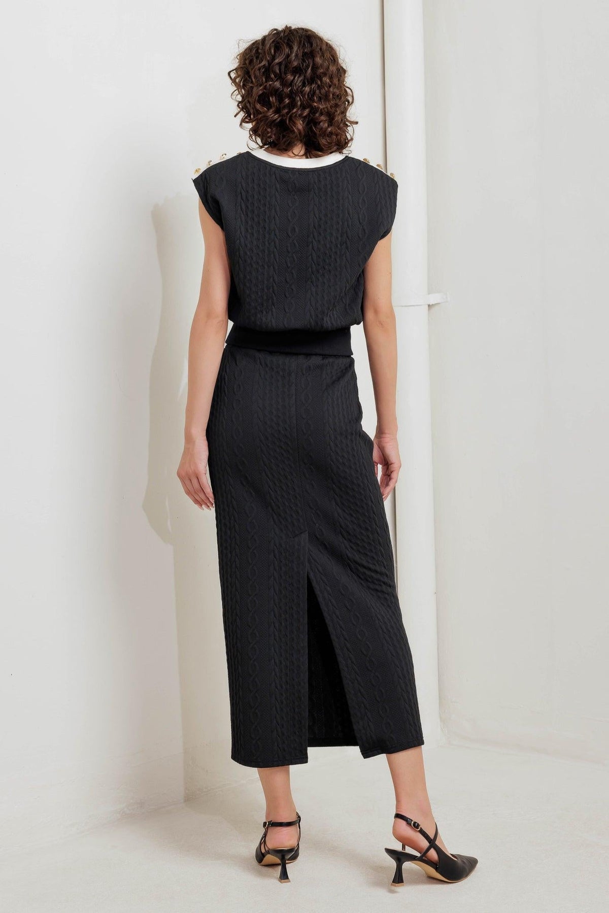 Black knit midi skirt with front slit and textured fabric; back view