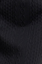 Close-up of black textured knit pattern on midi skirt fabric