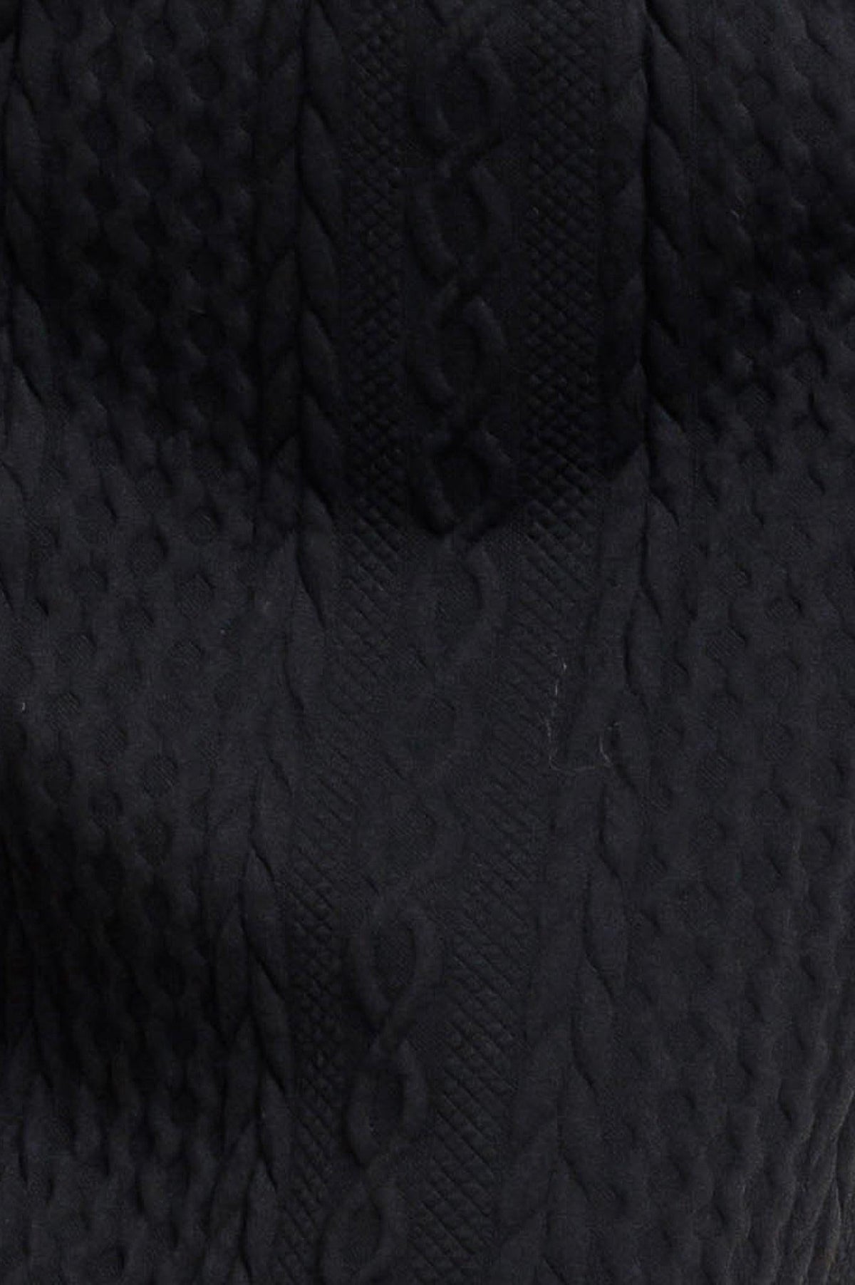 Close-up of black textured knit pattern on midi skirt fabric