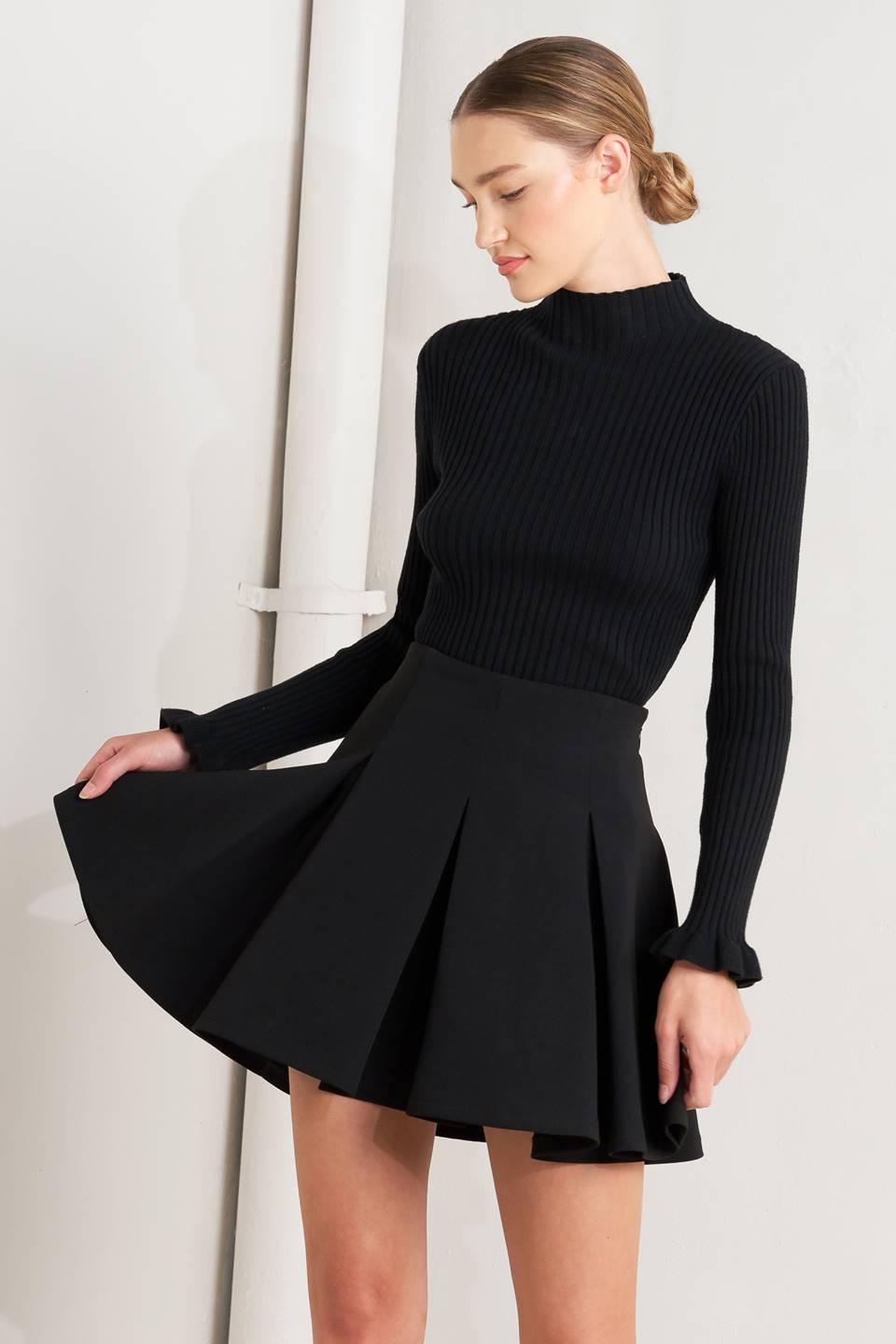 Black woven mini skirt with structured pleats and flared A-line silhouette