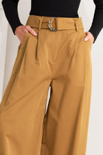 Camel woven pants close-up: belt buckle, fly seam, and side pocket openings