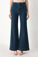 Indigo denim flare pants with central front seam, belt loops, and wide leg openings