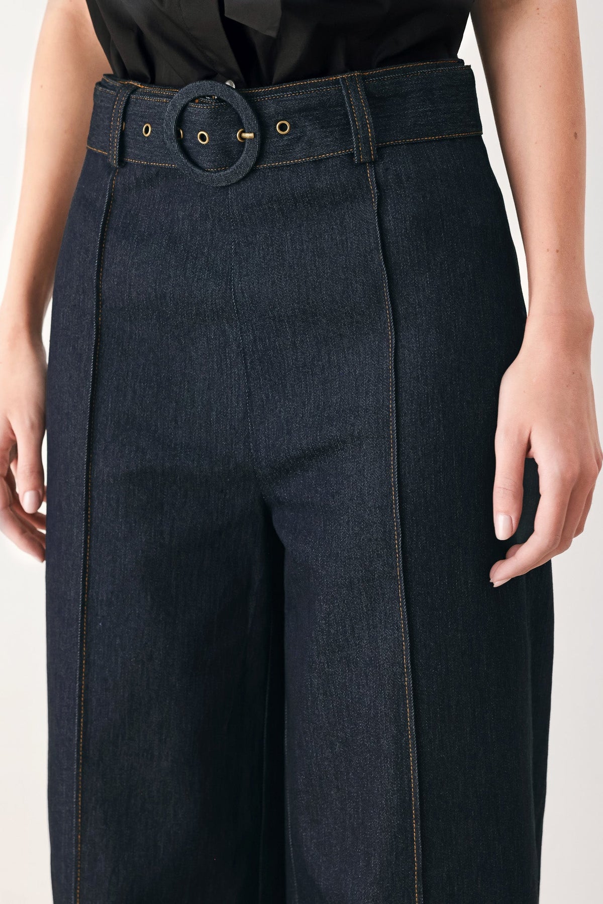 Dark denim pants with round buckle waistband and belt loops, contrast seam stitching