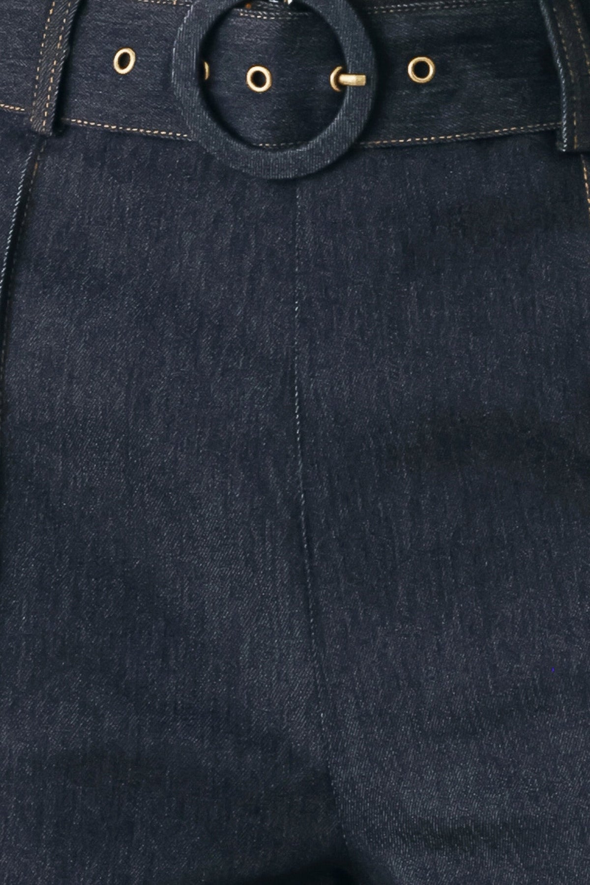 Dark denim waistband close-up with round buckle, belt loops, and gold-tone rivets