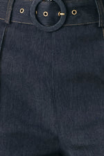 Dark denim waistband close-up with round buckle, belt loops, and gold-tone rivets