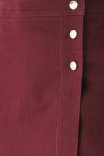 Burgundy woven skort close-up of button placket and fabric seam