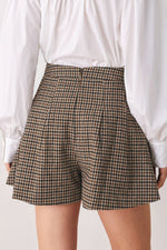 Close-up of brown and black tweed check skort waist and pleated shorts