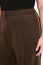 Brown pants close-up: waistband with pleat and vertical contrast side stripe