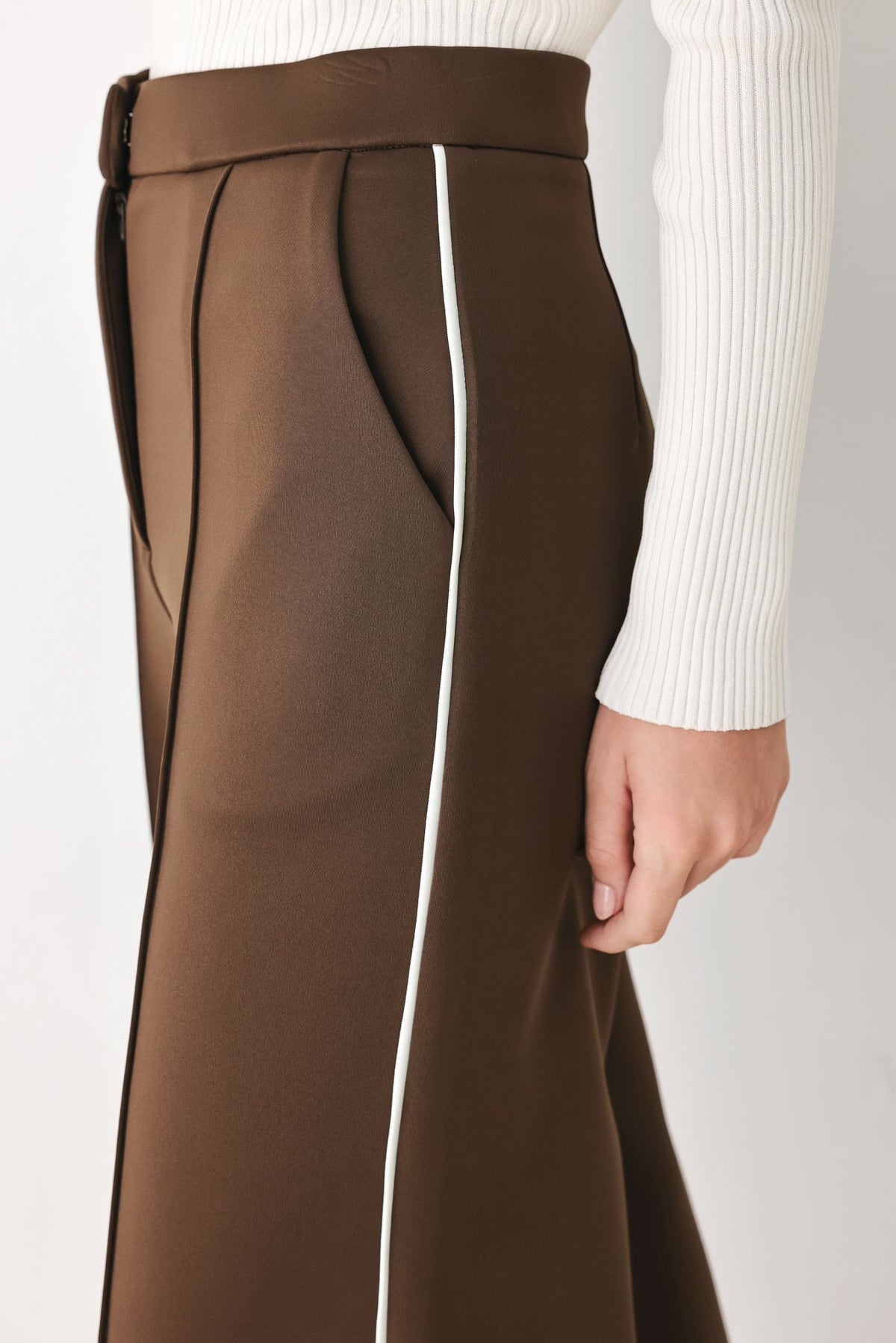 Brown pants close-up showing waistband, darts, and white side stripe panel