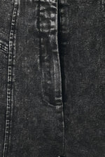 Black denim fabric close-up with textured wash and visible stitching