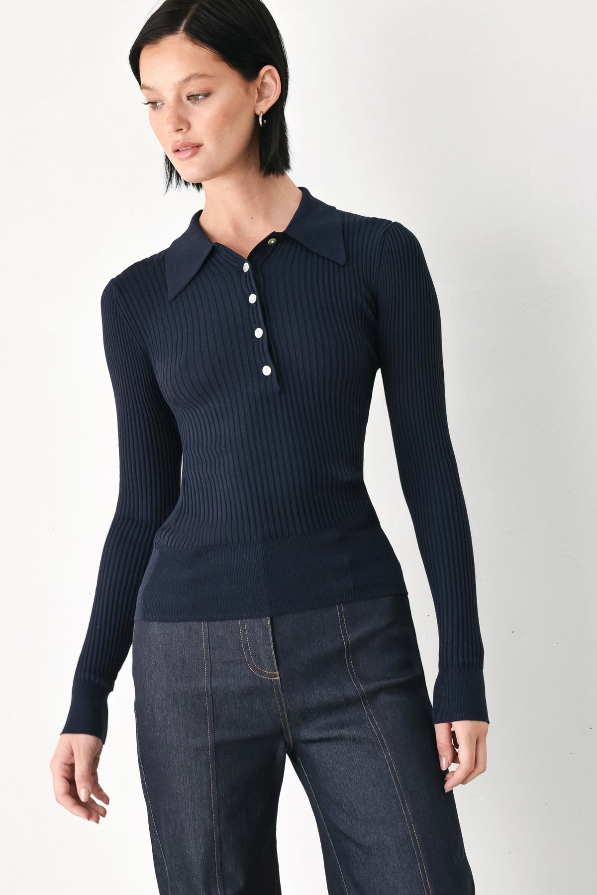 Navy ribbed knit polo top with pointed collar and button placket, long sleeves.