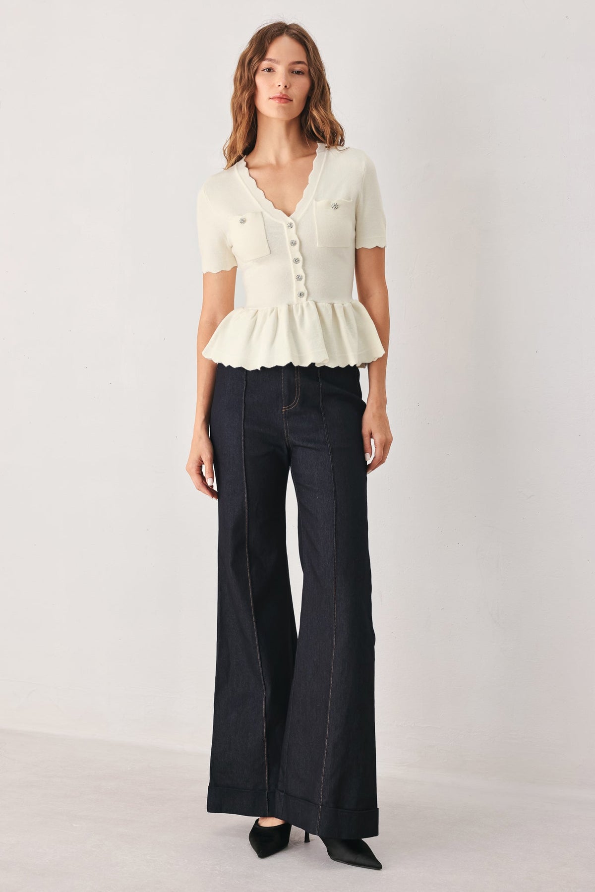 Cream knit sweater top with button front, chest pockets, and short-sleeve peplum