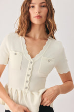Cream knit sweater top with scalloped V-neck and front button closure; chest pockets