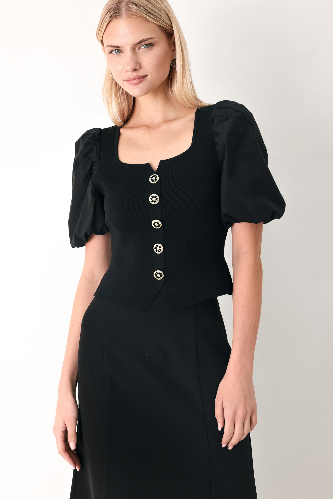 Black sweater-knit top with square neckline, short puff sleeves, and gold button placket