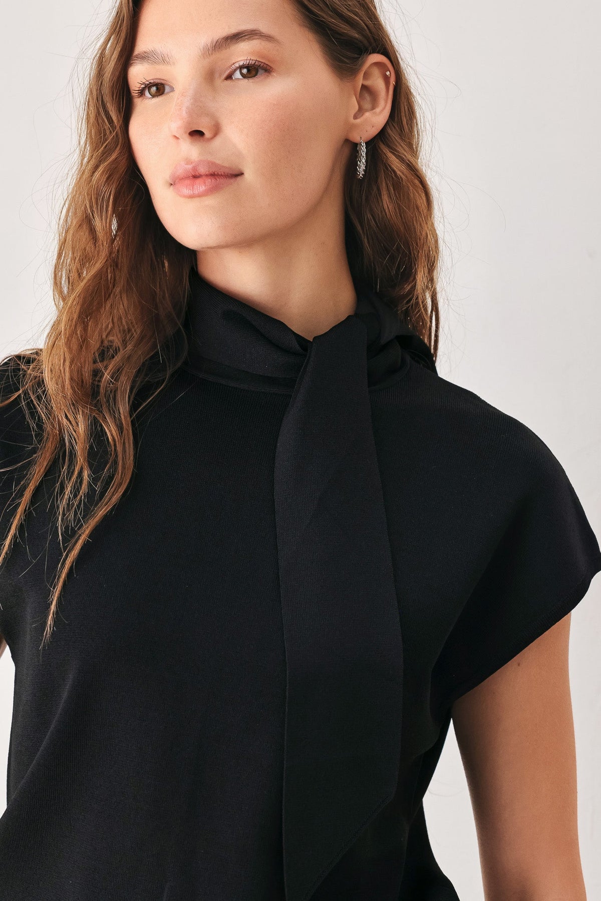 Black knit top with draped scarf neck tie at the high collar